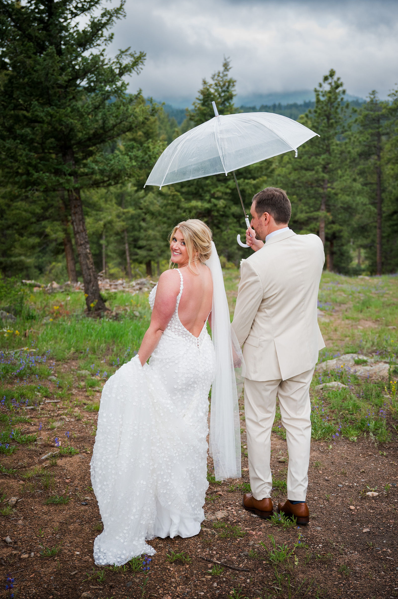 Bride and groom under a clear umbrella in the rain at a Colorado wedding