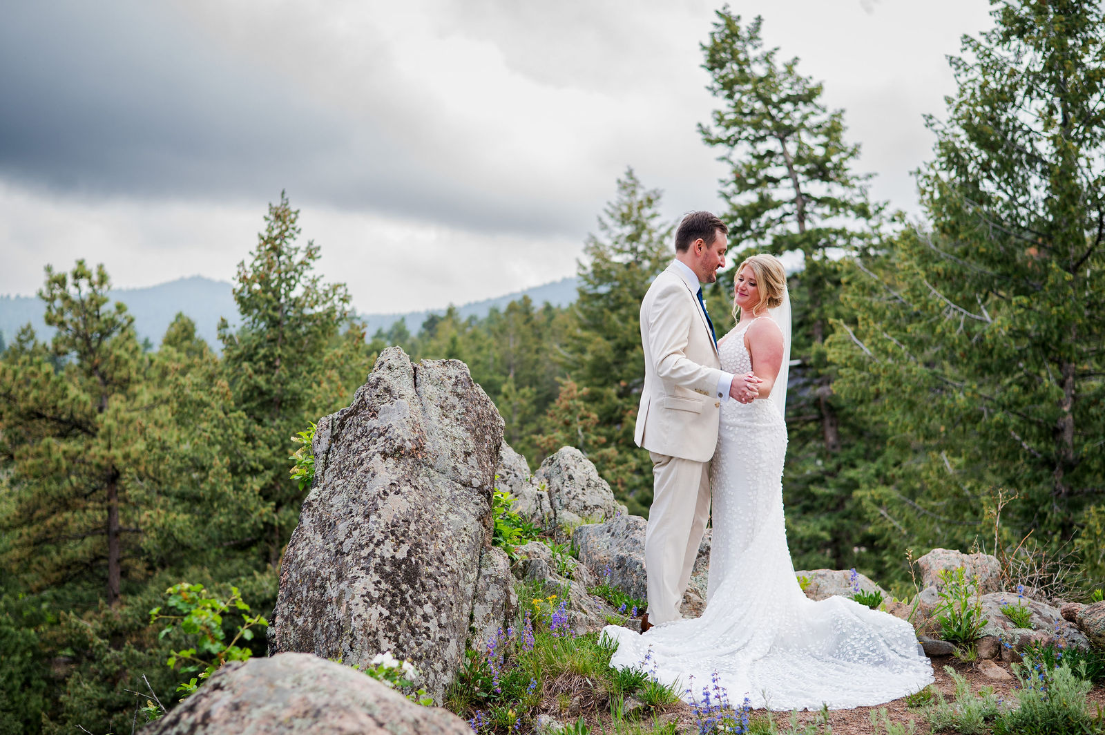 Bride and groom on the rocks with the veil blowing at a Colorado mountain wedding