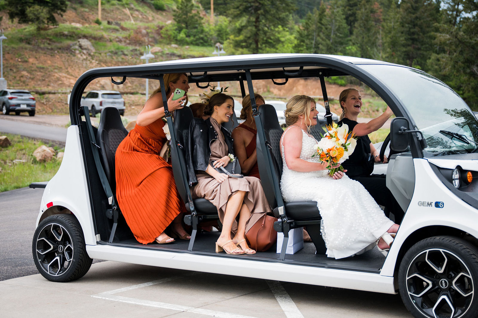 Wedding party riding a golf cart at The Woodlands wedding venue in Colorado