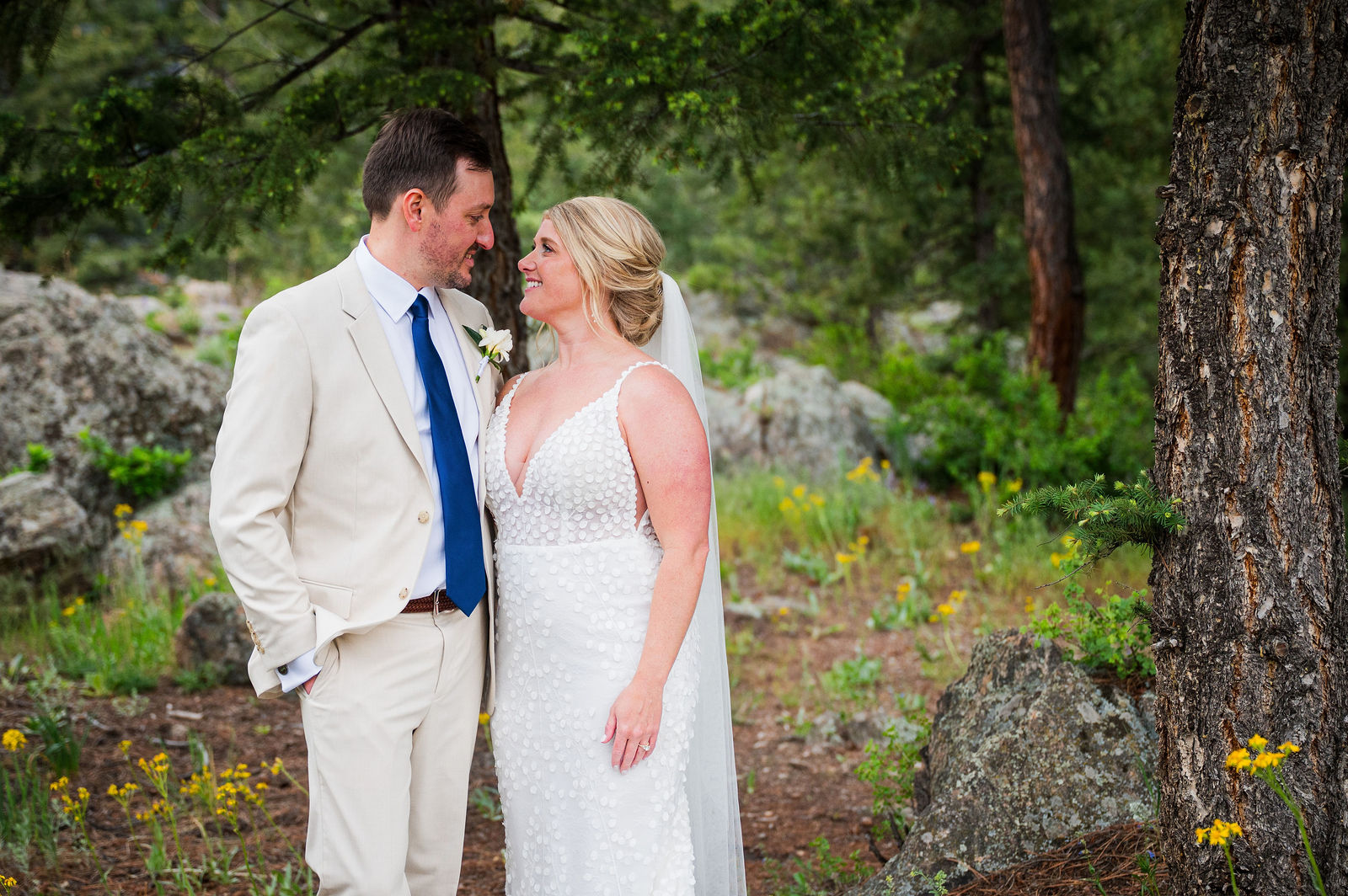 Bride and groom laughing together in the trees at a Colorado wedding