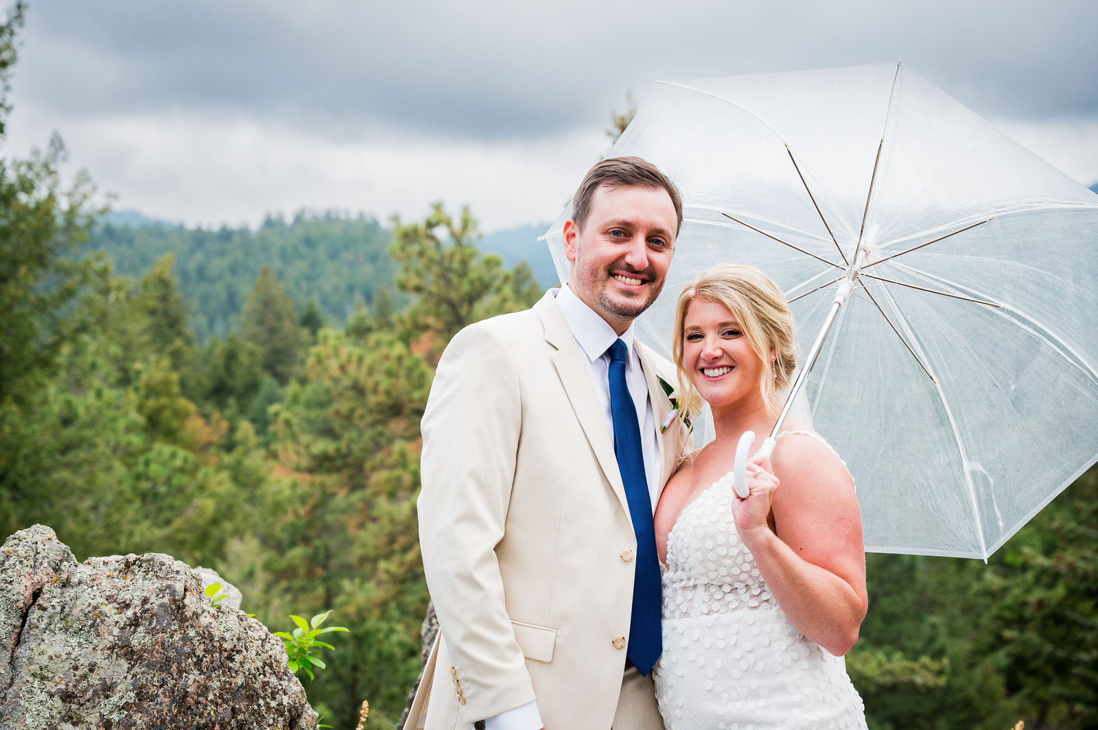 Bride and groom with an umbrella and a mountain view at The Woodlands Colorado