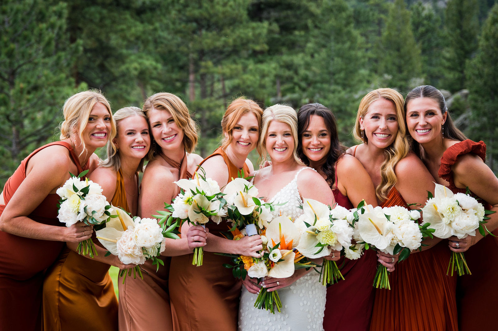 Bridesmaids in rust dresses holding bouquets at The Woodlands Colorado