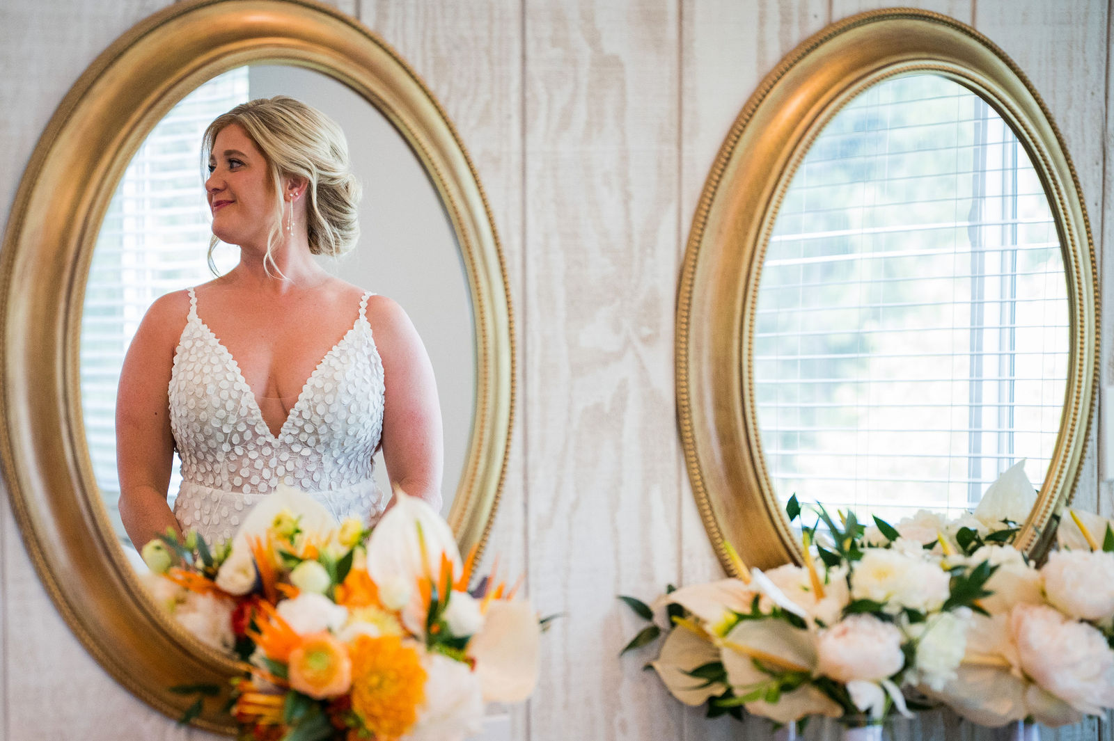 Bride in her wedding dress between gold mirrors with orange florals in Colorado