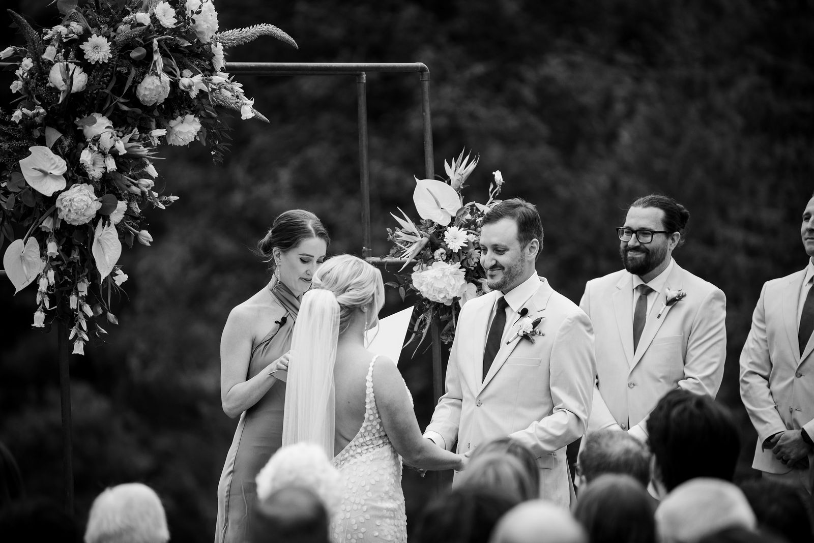 Bride and groom exchanging vows under the floral arch at The Woodlands