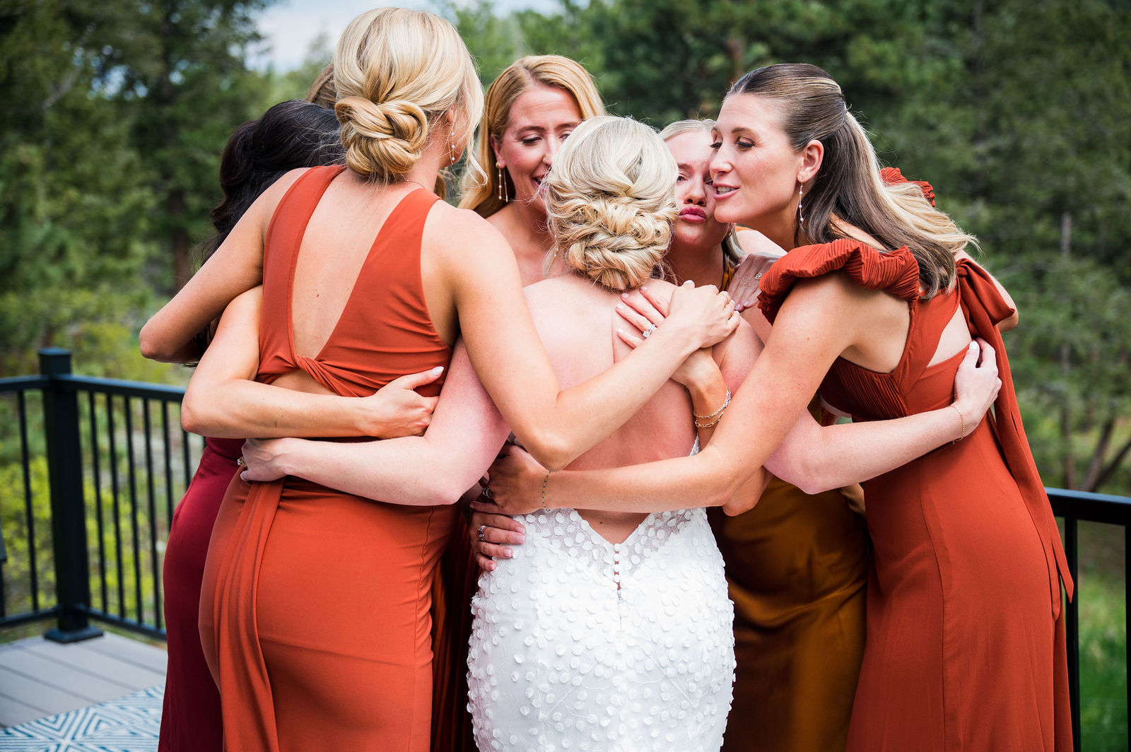 Bride and bridesmaids hugging on the deck at The Woodlands in Morrison Colorado