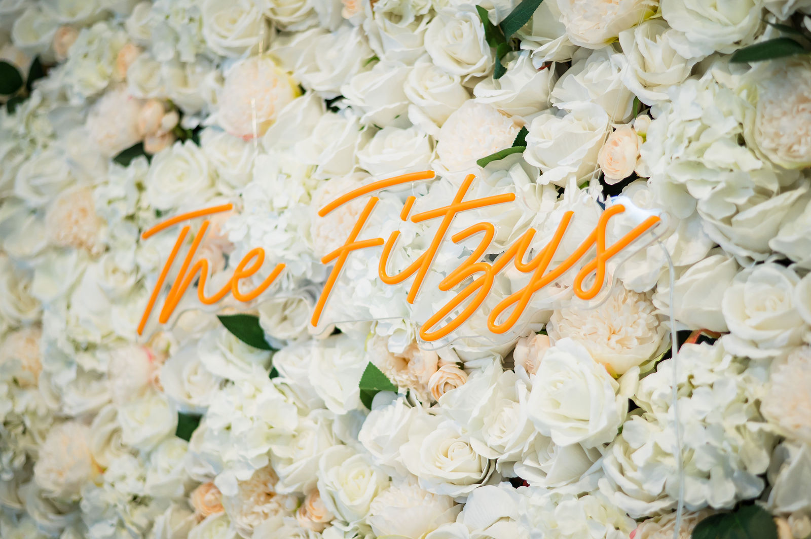 The Fitzys neon sign on a white flower wall at a Woodlands Colorado wedding