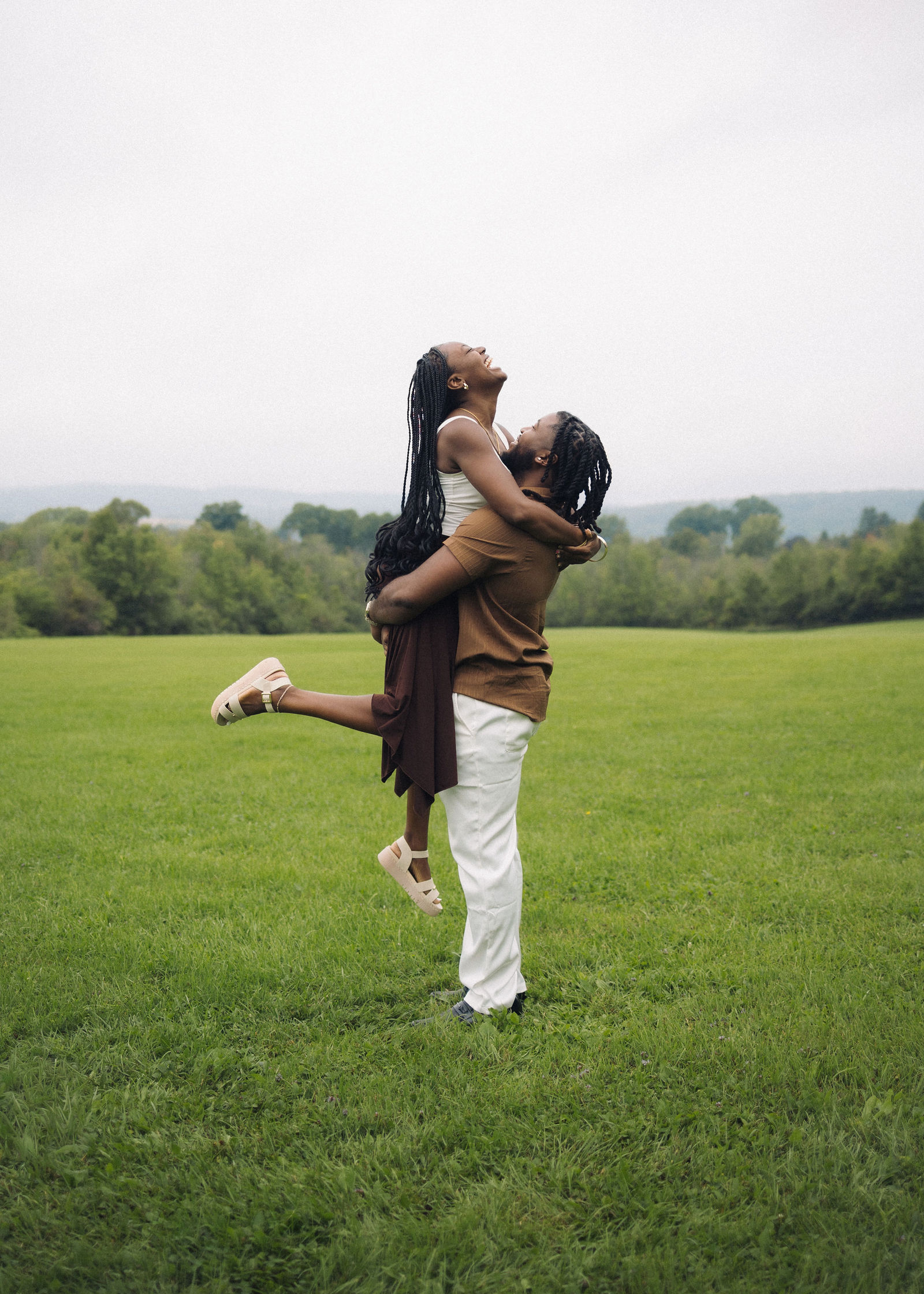 A woman being picked up in an open field while laughing