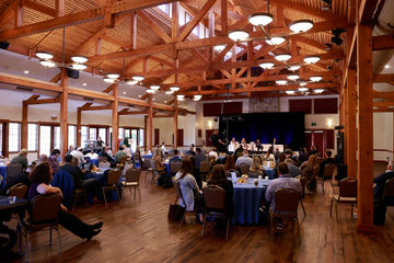 North Capitol Summit guests seated at tables beneath exposed timber beams at This Is the Place Heritage Park