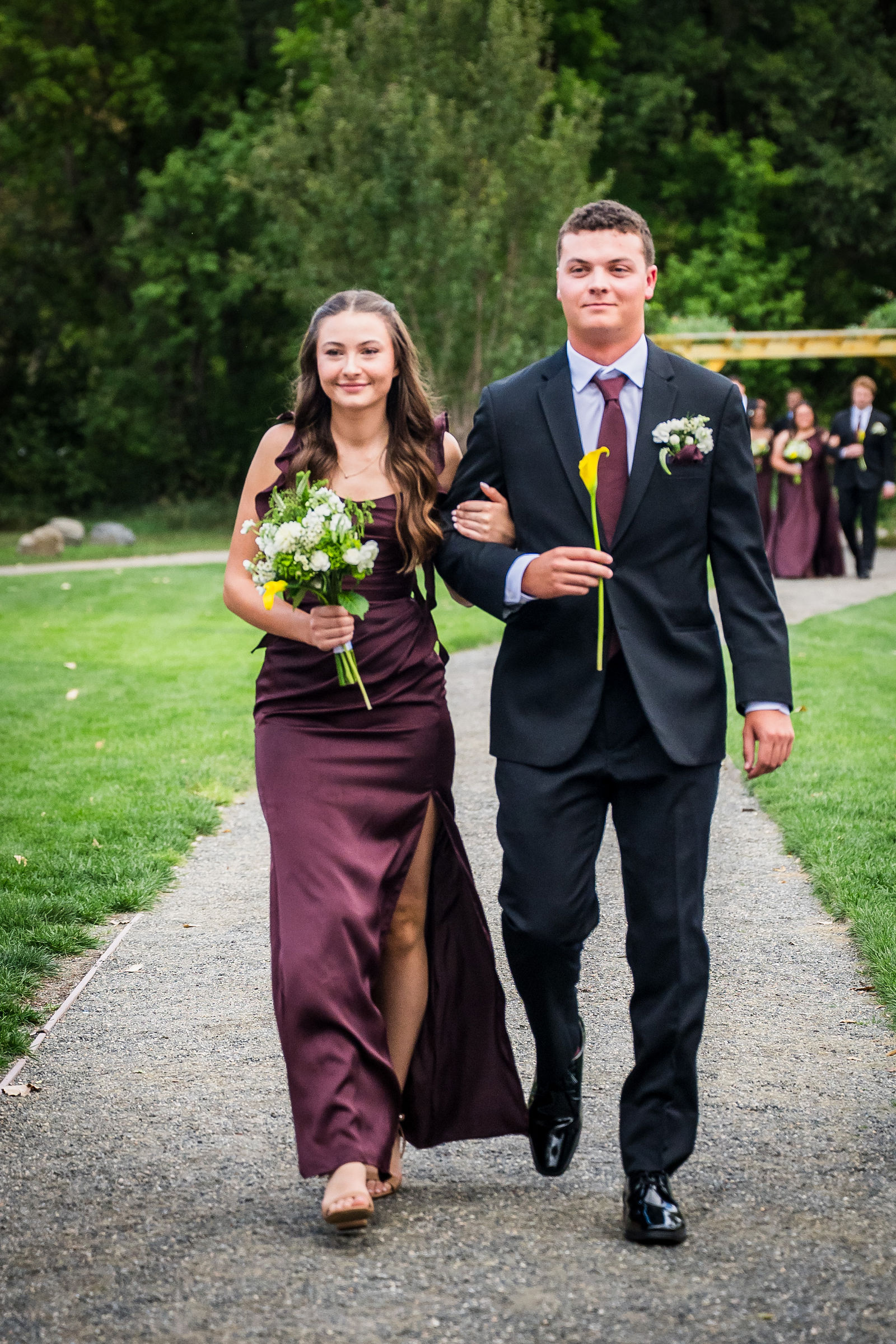 Bridesmaid carrying a single yellow flower down the aisle