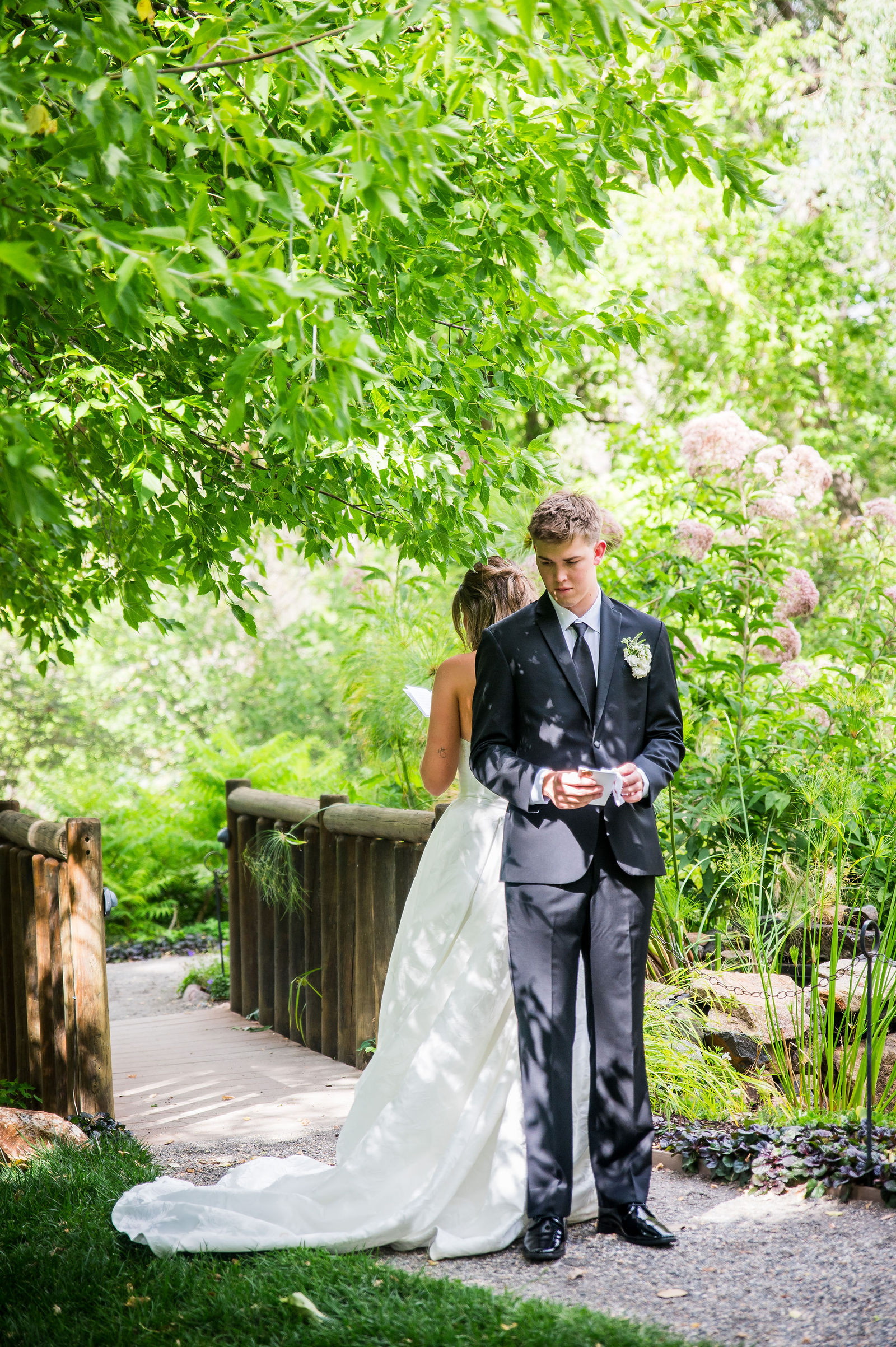 Bride and groom standing back to back reading private vows at Denver Botanic Gardens Chatfield Farms