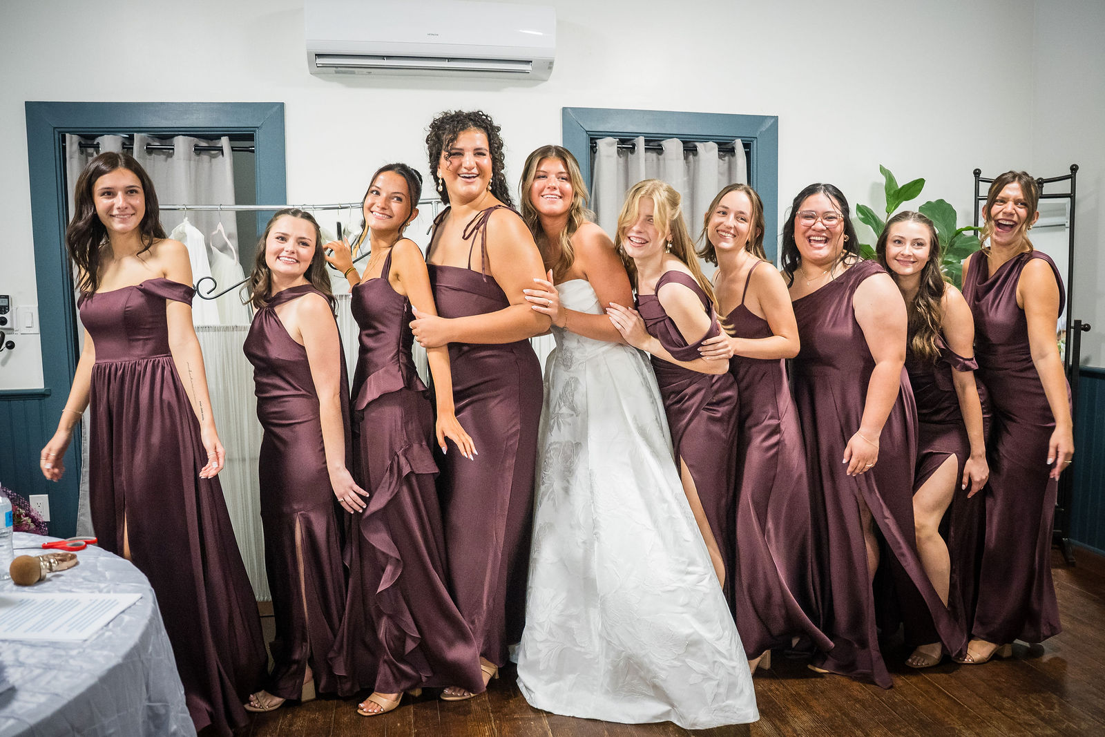 Bride with all nine of her bridesmaids in deep plum