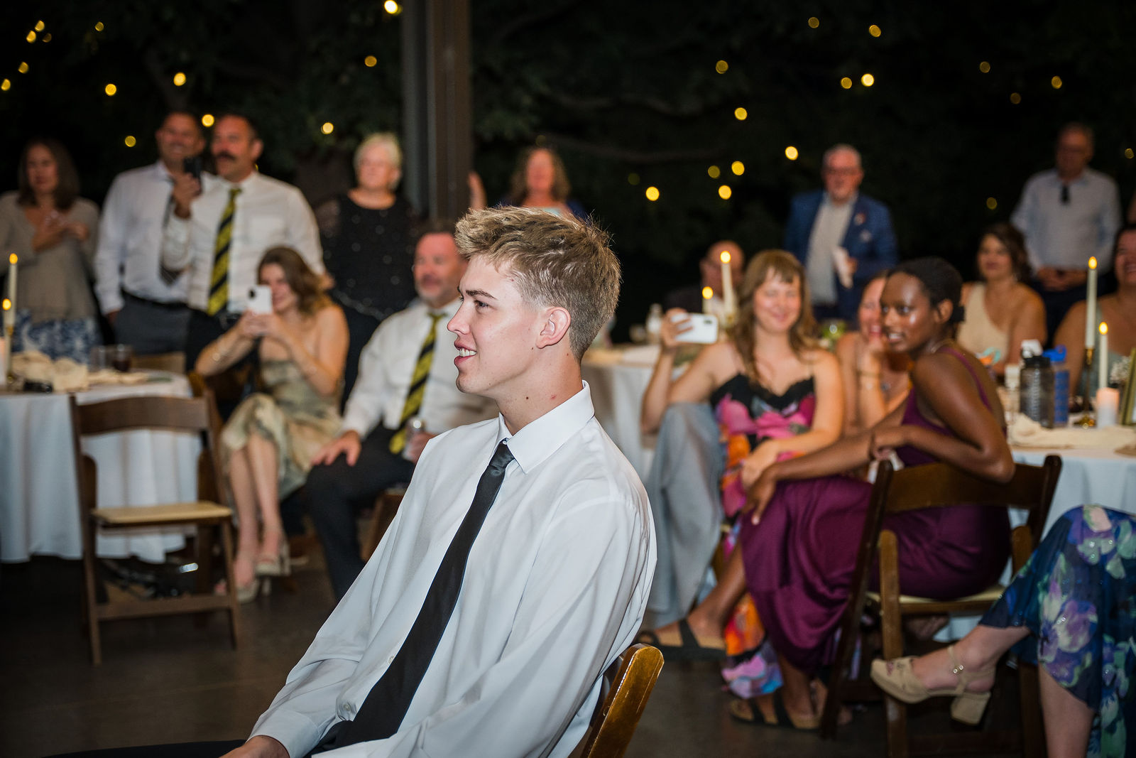 Groom laughing during his bride’s surprise dance