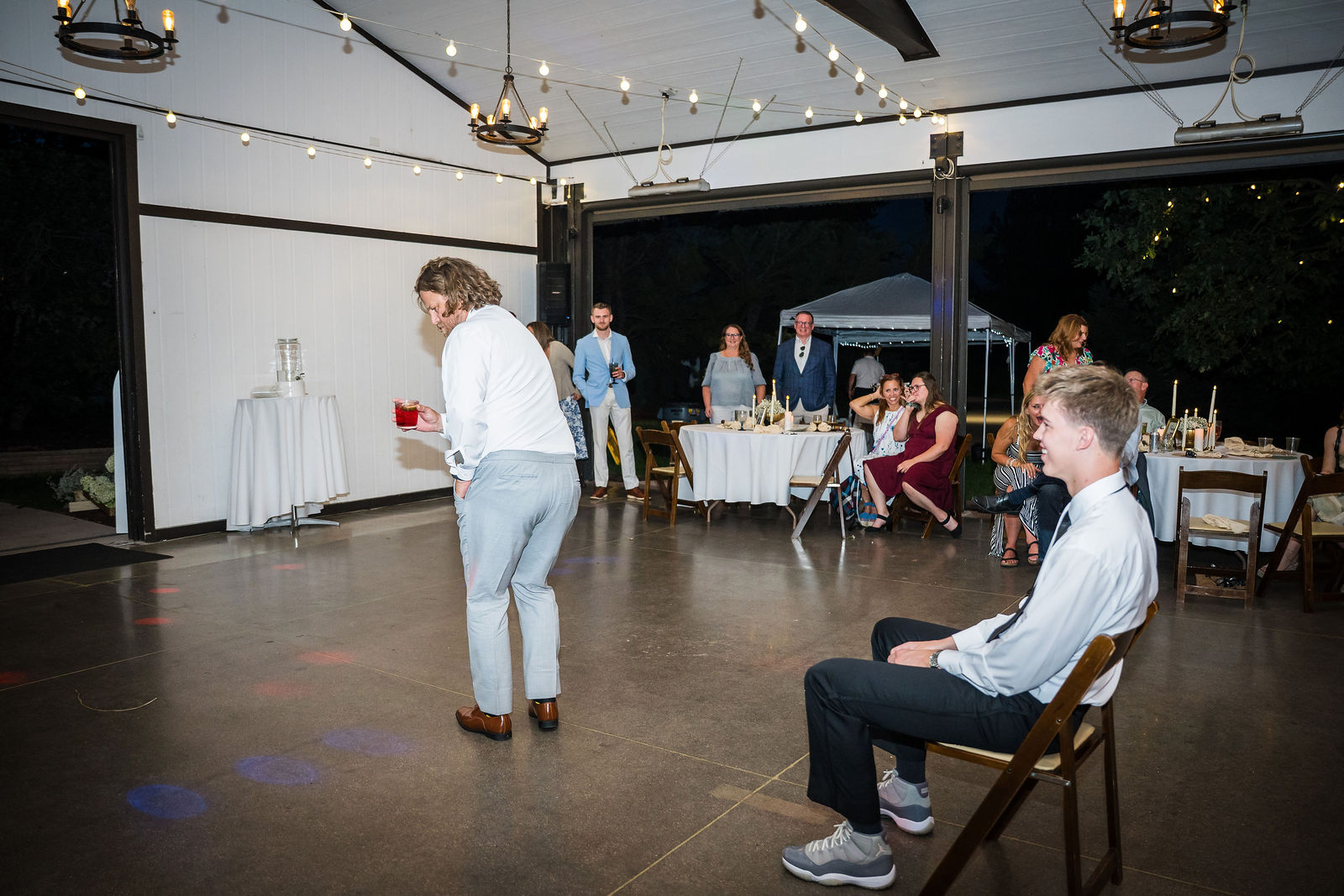 Groom sitting in a chair in the middle of the barn for a surprise dance