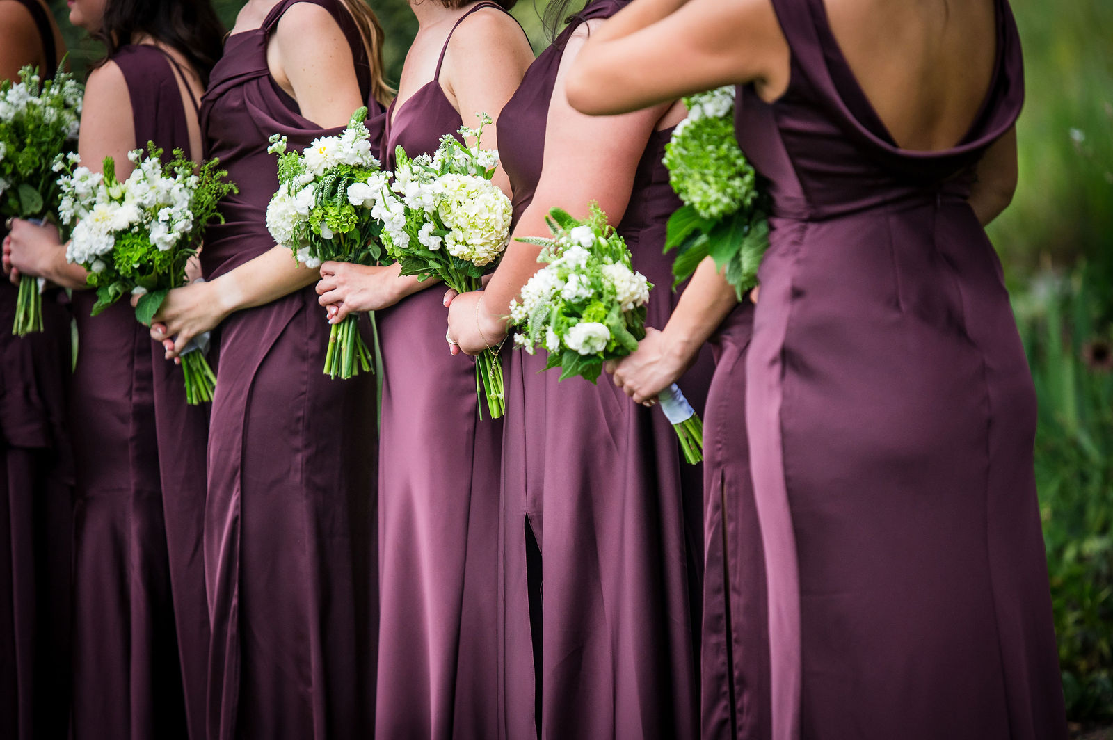 Bridesmaids holding white and green bouquets during the ceremony