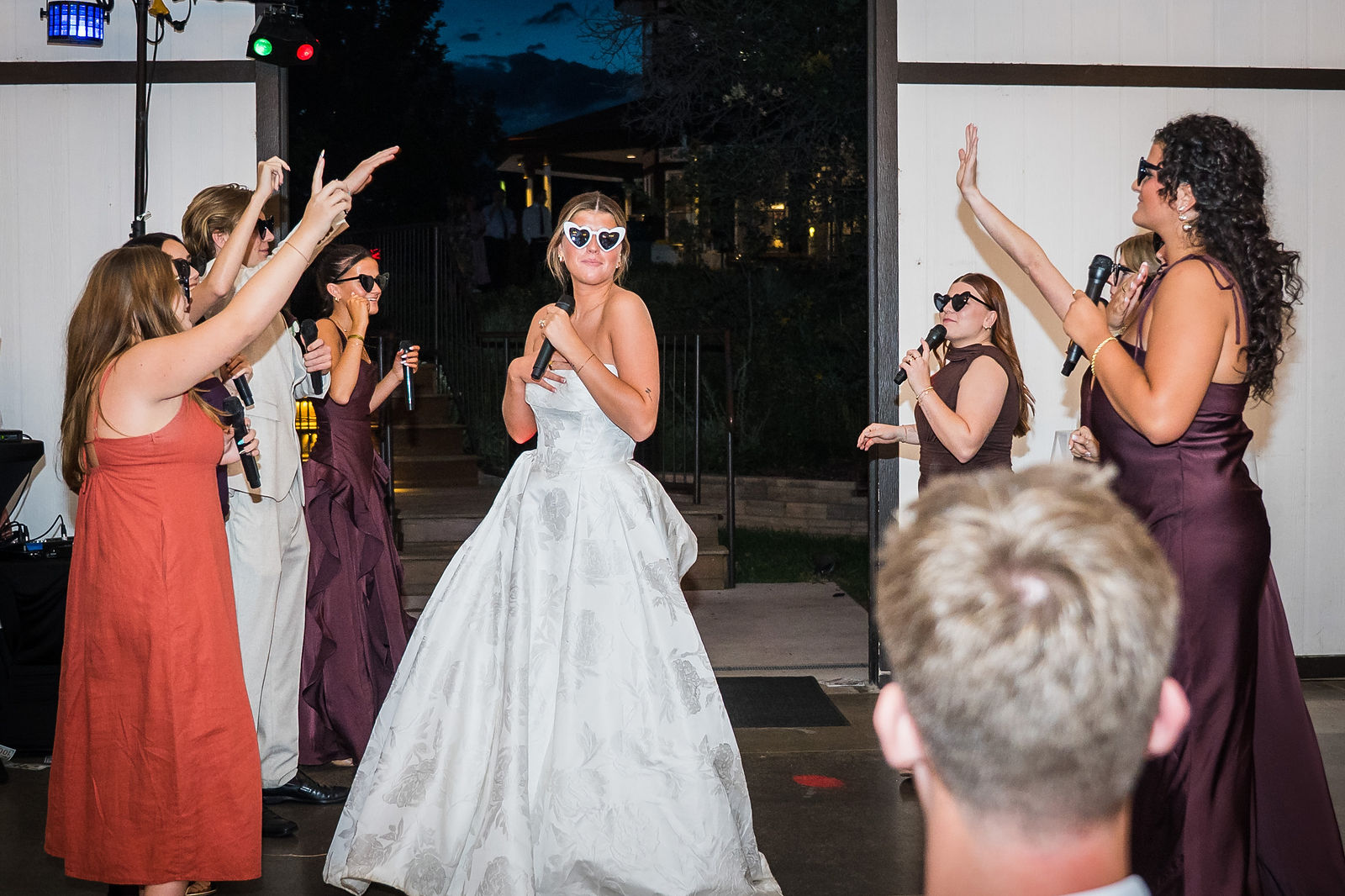 Bride dancing in sunglasses during a surprise wedding performance