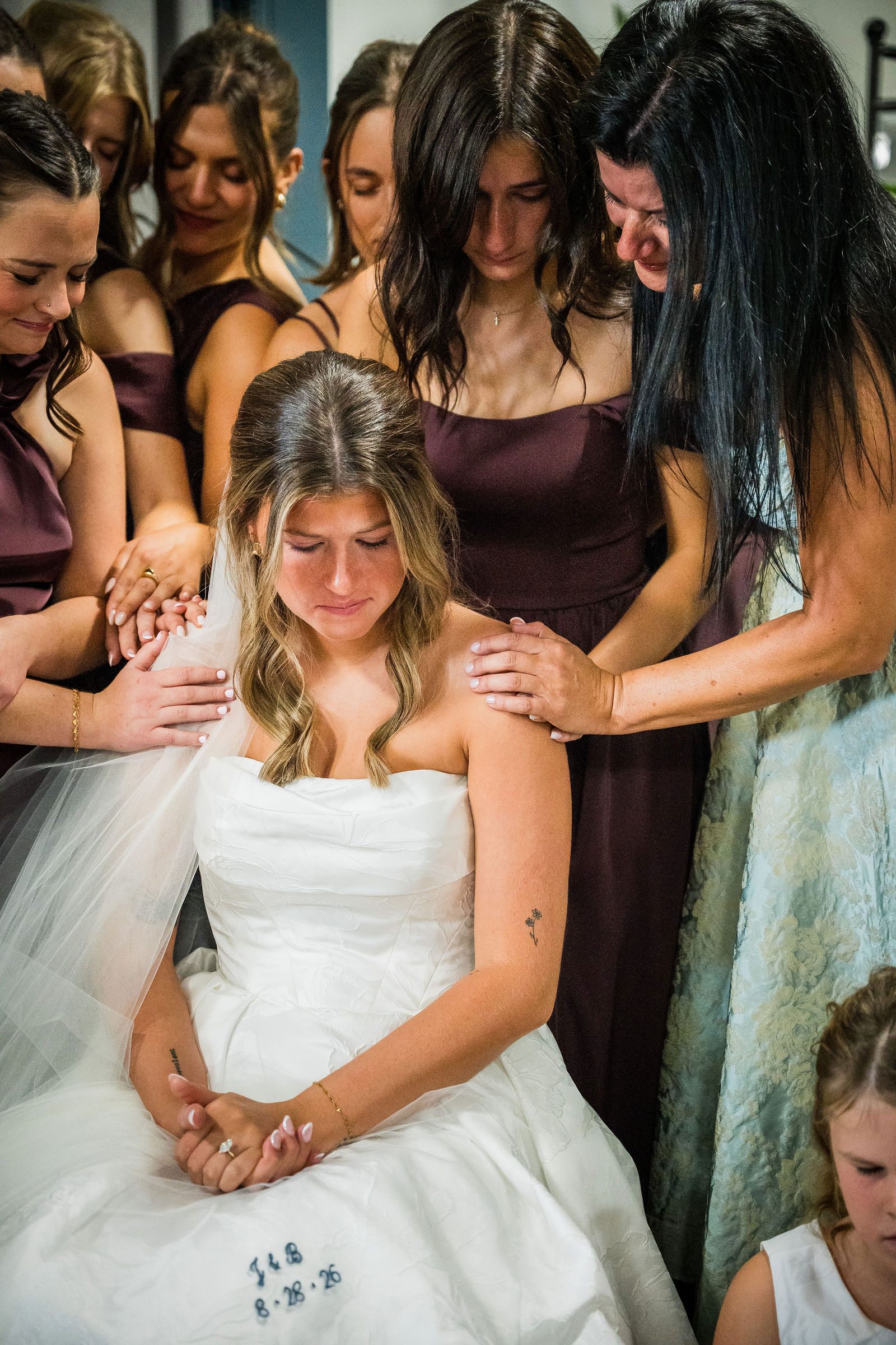 Bridesmaids laying hands on the bride and praying over her