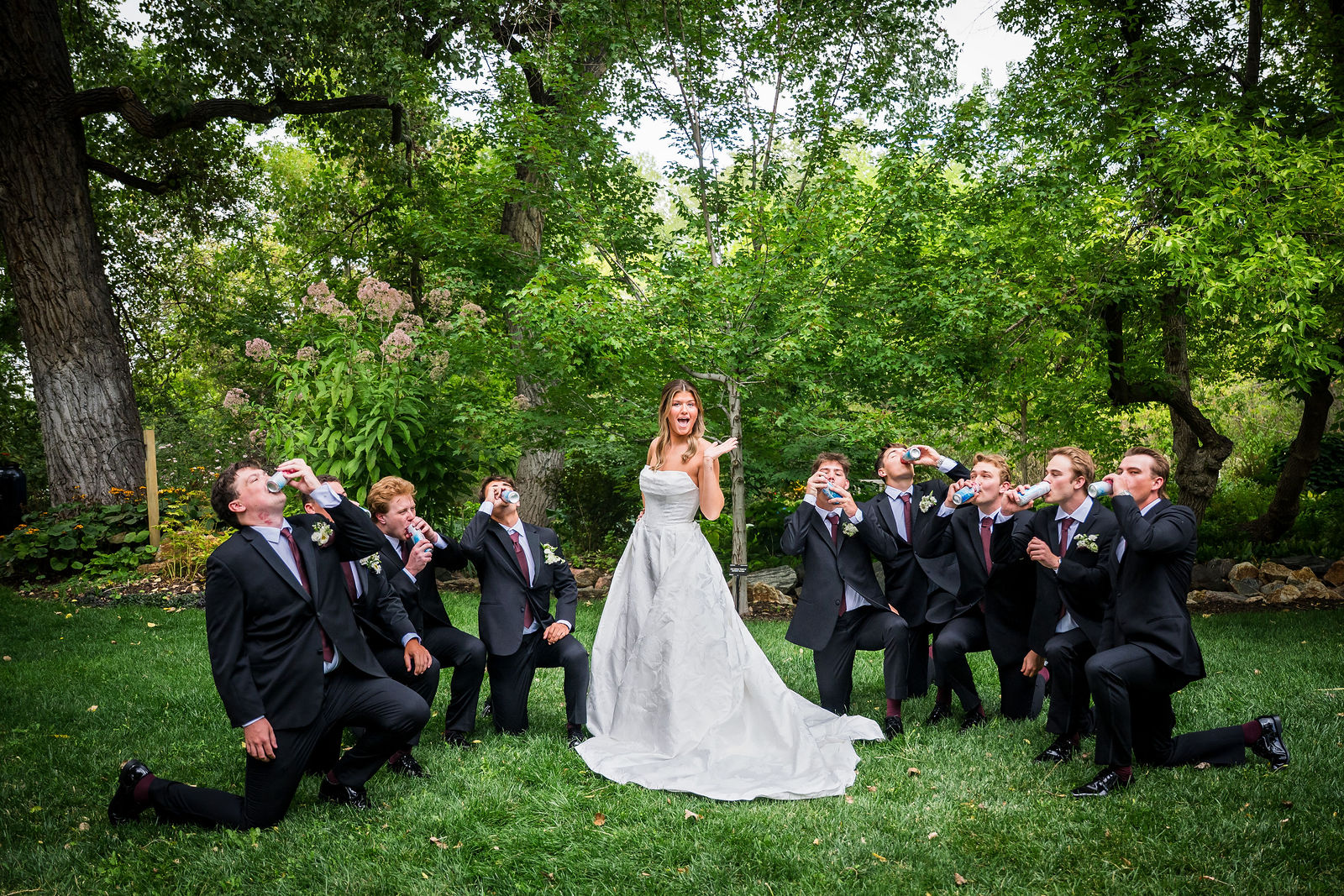 Groomsmen kneeling in the grass after being iced by the bride